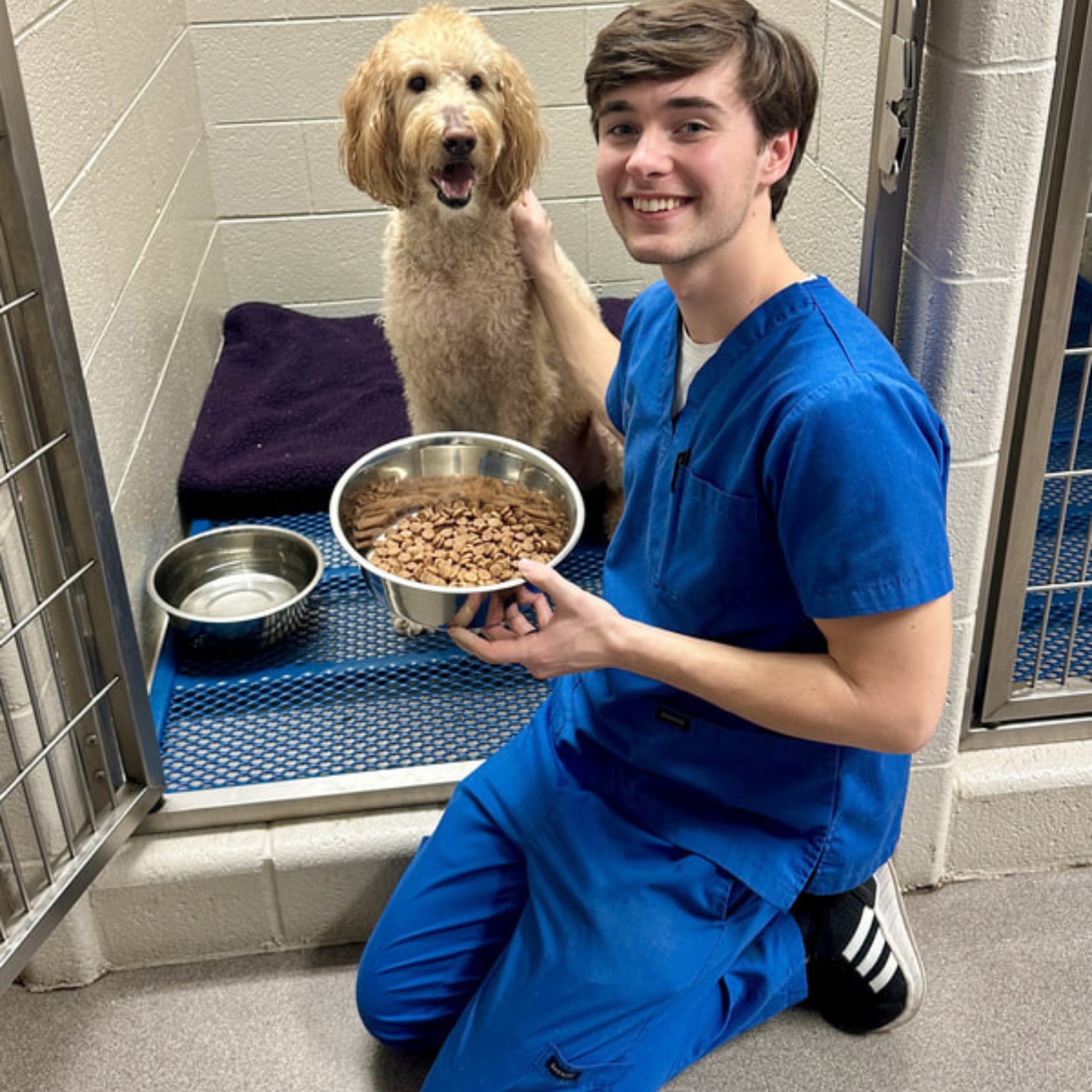 a man in scrubs holding a bowl of food and a dog